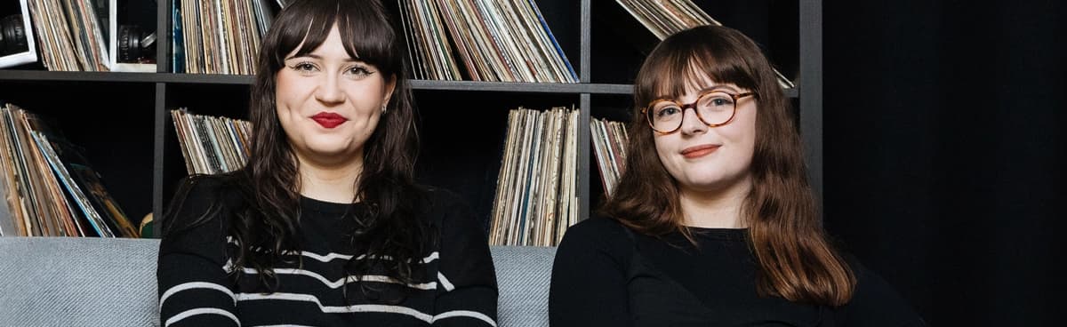 Pesquisadores musicais sentam-se em frente a uma coleção de discos de vinil